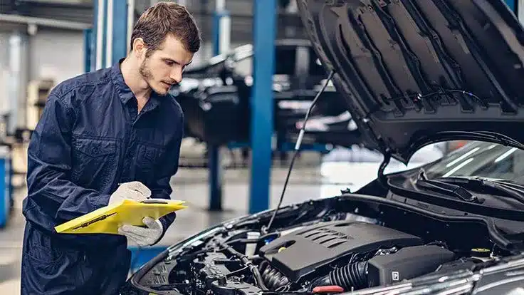 an image of a person standing in front of car pouring oil into its engine
