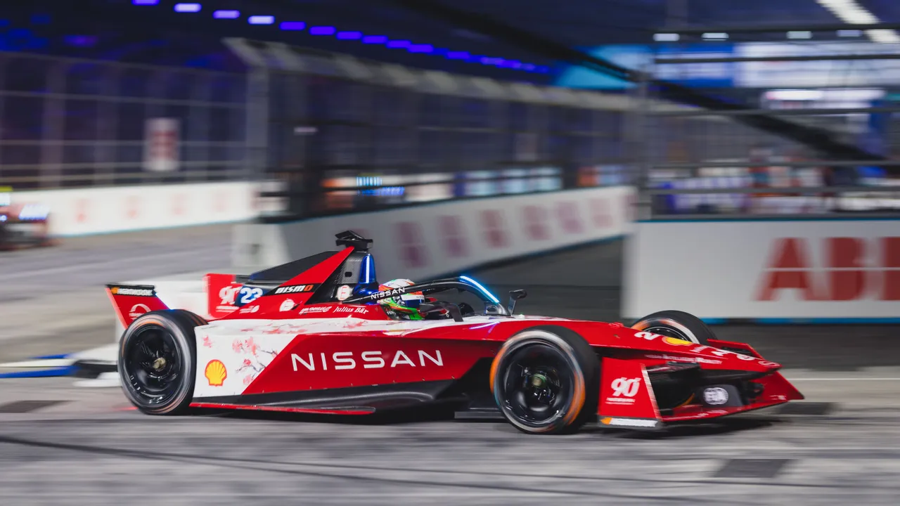 A red and white Nissan Formula E electric race car driving at high speed on a track.