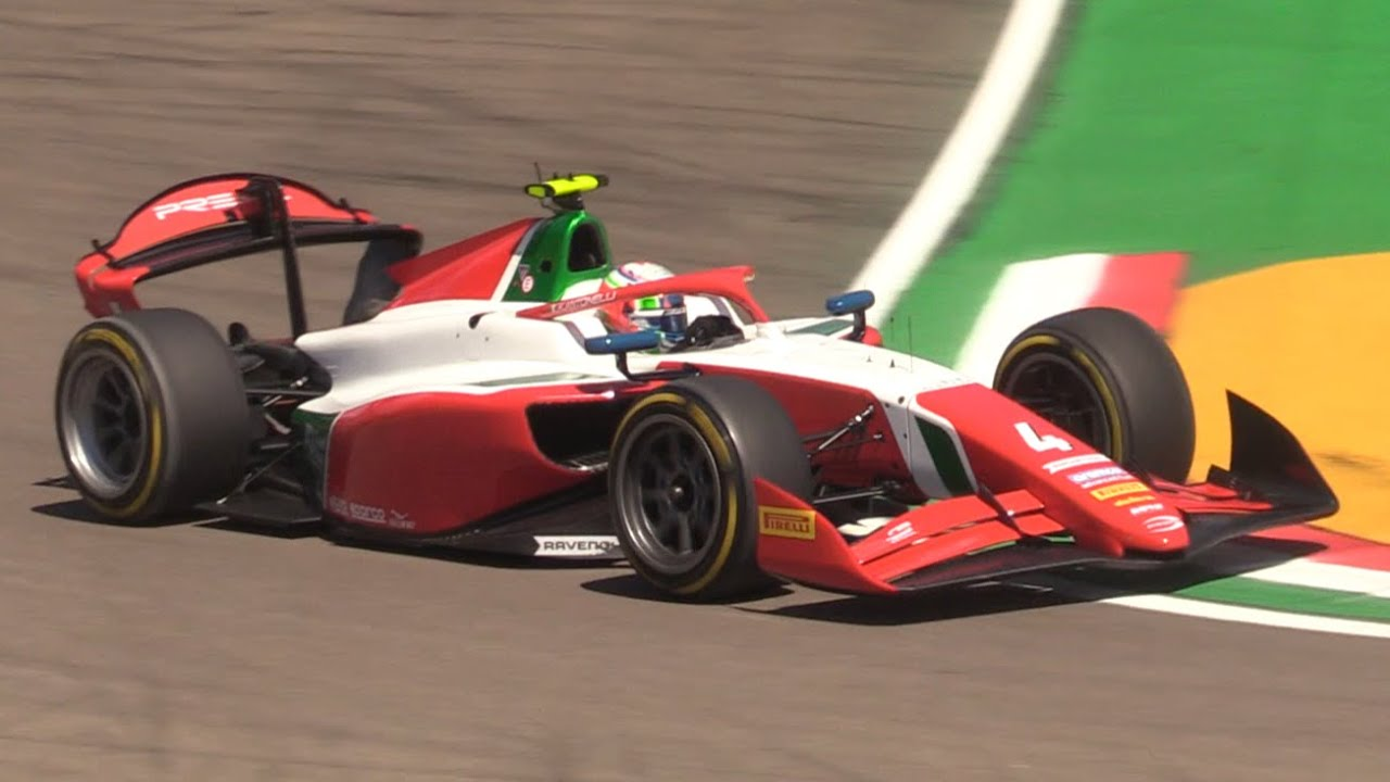 A red, white, and green race car driving through a curve on a professional circuit track.