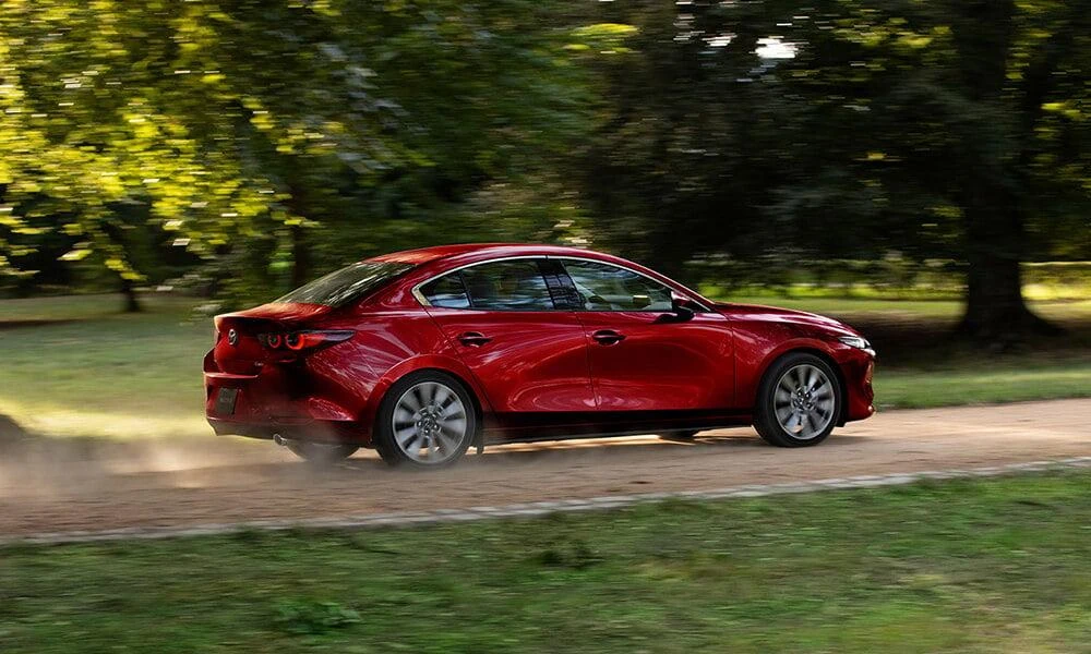 Red Mazda3 sedan parked on a quiet road.