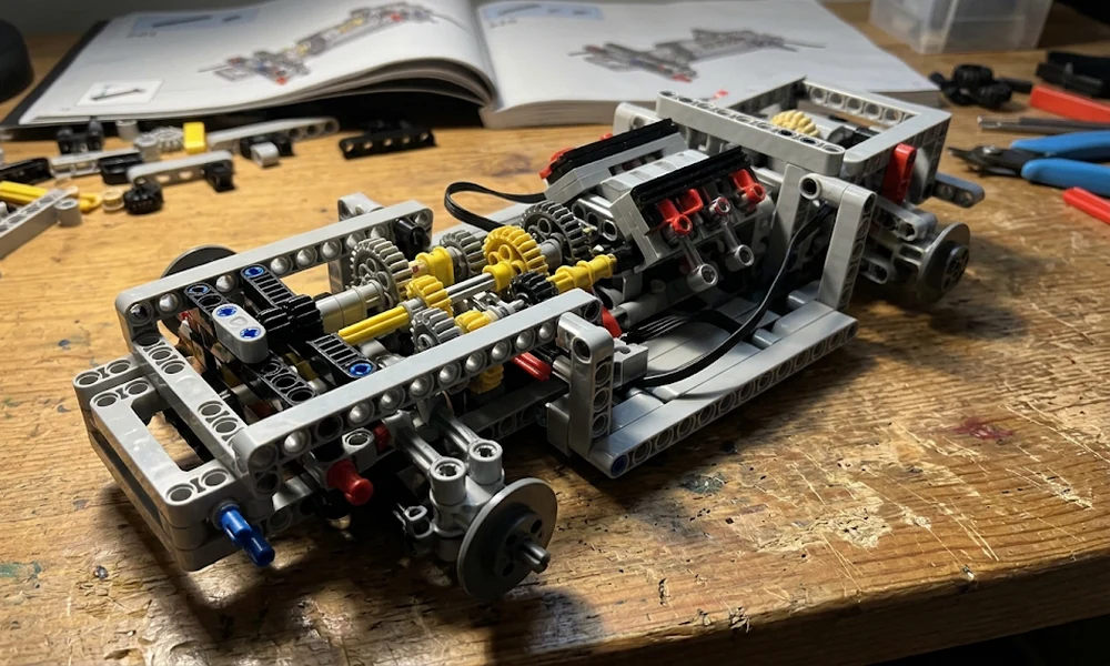 LEGO Technic chassis with gears, axles, and a gearbox next to an instruction book