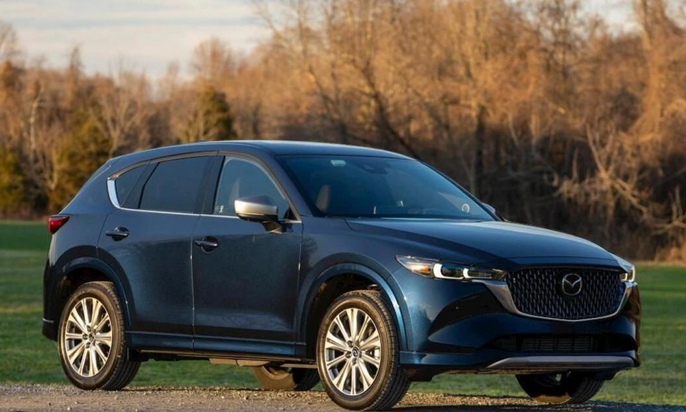 Dark blue Mazda CX-5 compact SUV in a green outdoor setting.