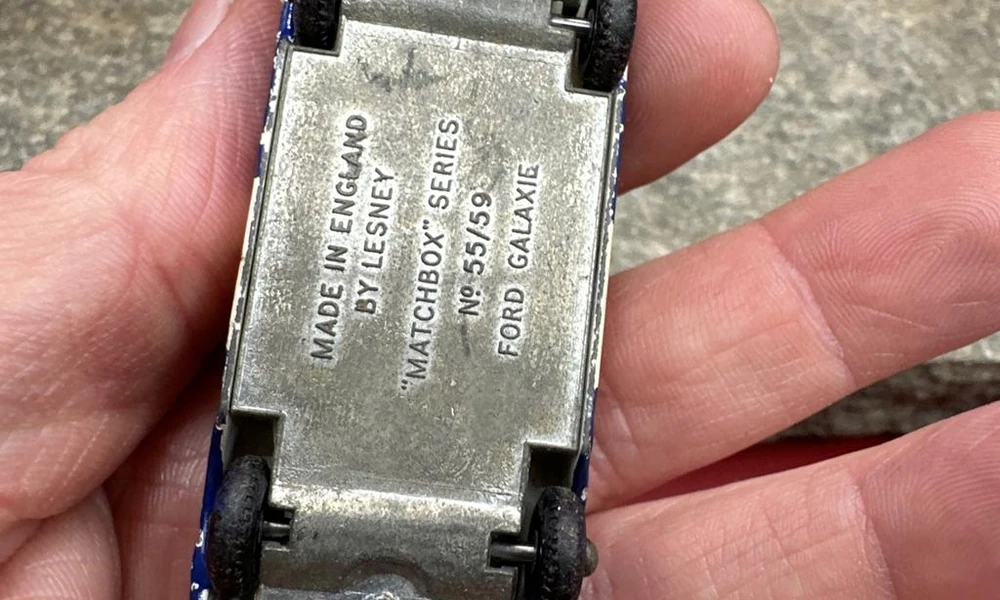 Collector examining the base and wheels of a vintage miniature die-cast car.