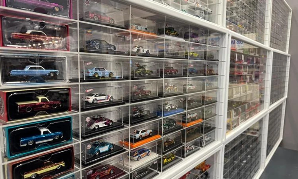 Miniature die-cast cars arranged in a clear compartmentalized collector display case.