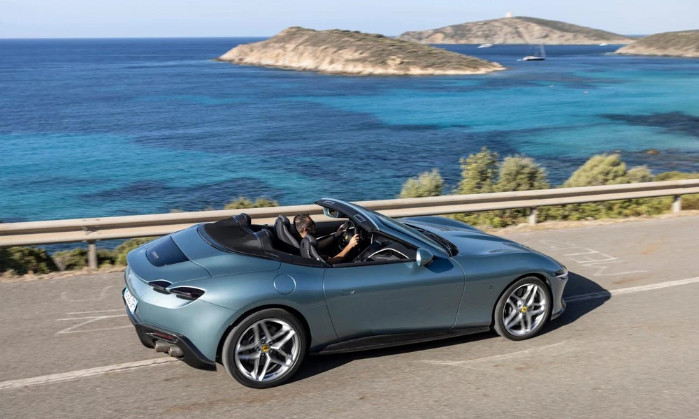 Convertible car with its roof lowered on a scenic road.