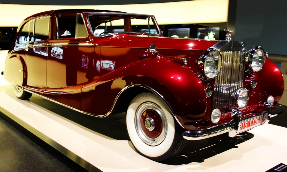 Red vintage luxury sedan with white-wall tires on display in a museum