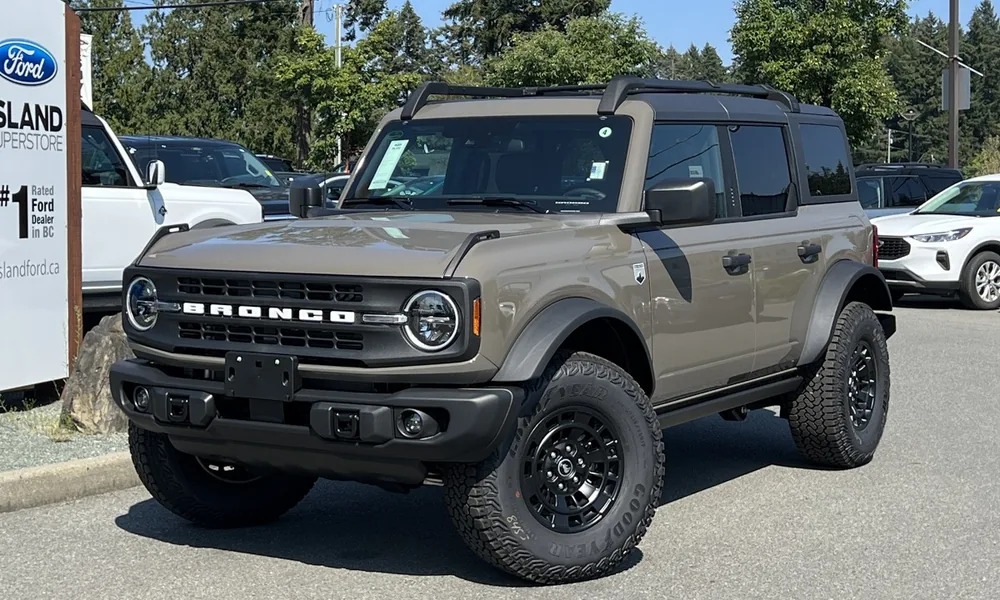 Gray-green Ford Bronco with off-road tires parked in a lot