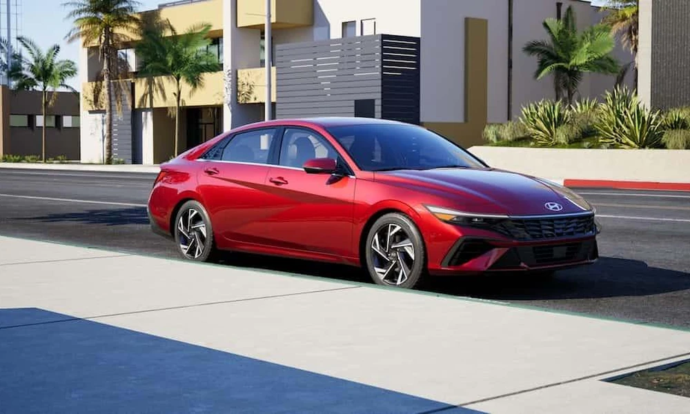Red Hyundai Elantra compact sedan parked outside a modern building.