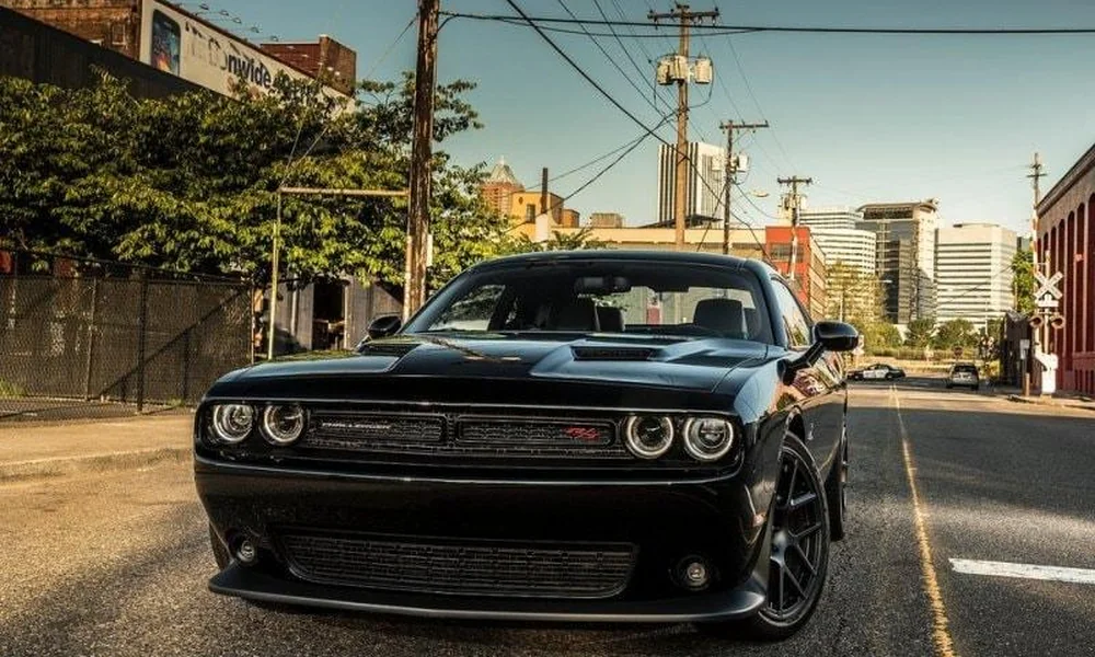 Black Dodge Challenger muscle car on an urban street.