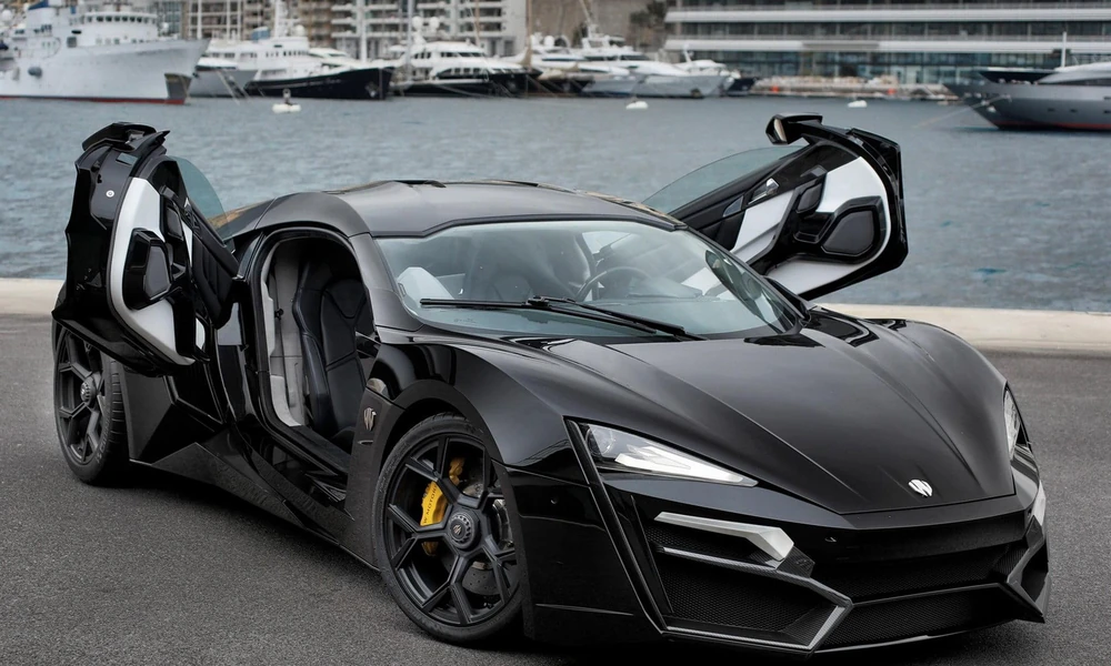Black W Motors Lykan HyperSport exotic supercar parked beside a waterfront.