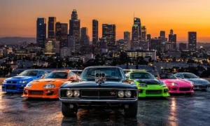 Fast and Furious cars lined up at sunset, including a black Dodge Charger, orange Toyota Supra, blue Nissan Skyline and green Mitsubishi Eclipse, with the Los Angeles skyline behind