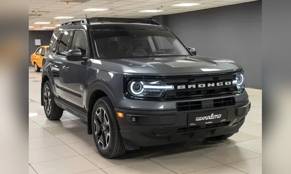 Dark gray Ford Bronco Sport with round LED headlights parked on a tiled showroom floor
