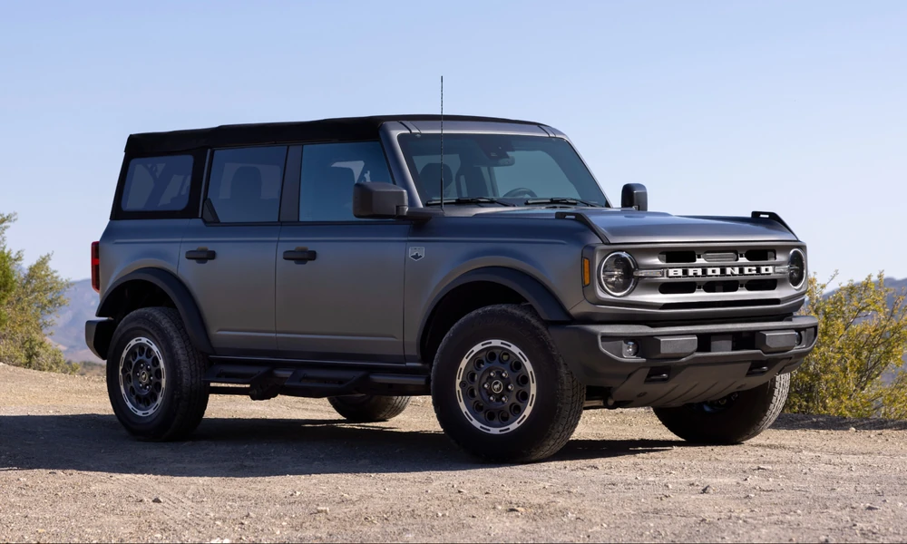 Gray four-door Ford Bronco with a soft top parked on a dirt trail