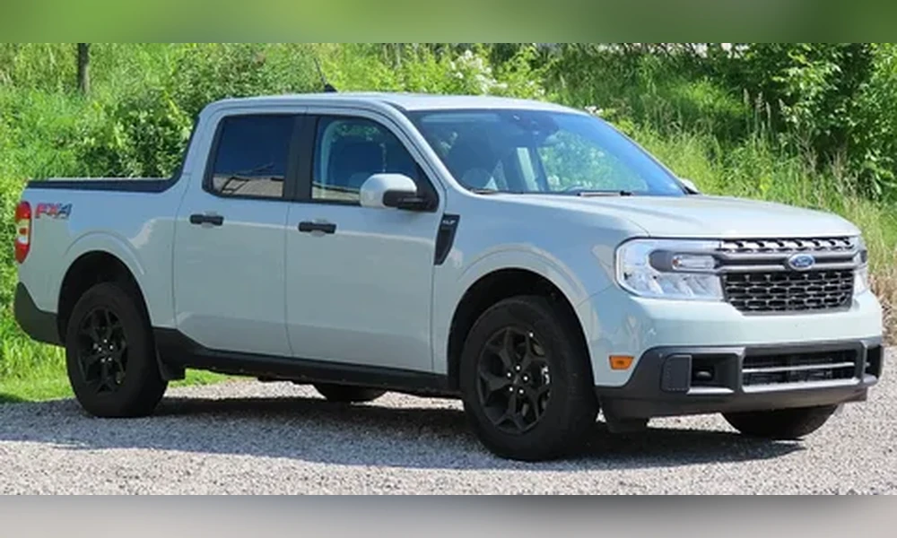 Light gray Ford Maverick compact pickup parked on gravel with green grass behind it