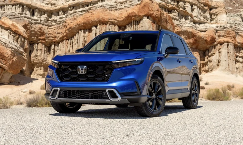 Blue Honda CR-V Hybrid SUV parked on a gravel lot in front of eroded sandstone cliffs