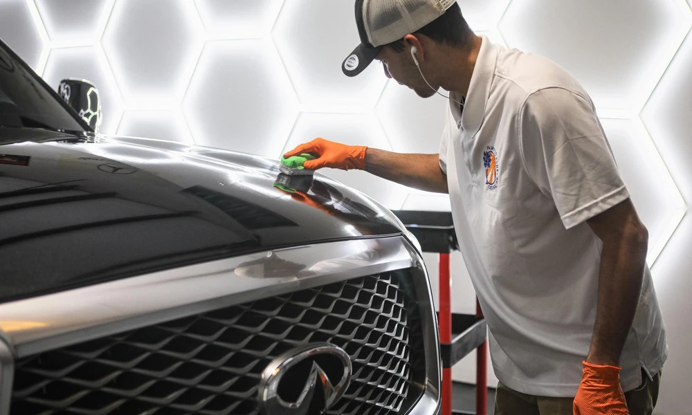 Professional ceramic coating being applied to a luxury SUV in a detailing workshop.
