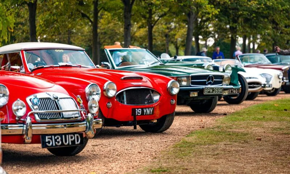 Red vintage sports car and silver classic coupe at a collector-car display.