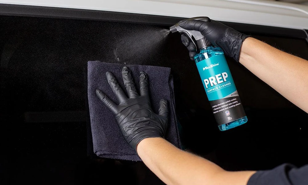 Detailer wiping car paint with a microfiber towel before ceramic coating.
