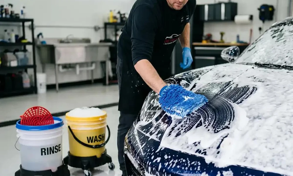Two-bucket washing method being used to clean a car safely.