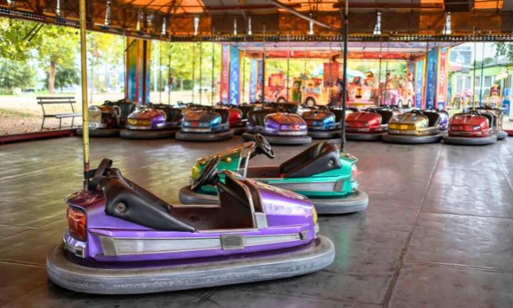 Traditional bumper cars with protective rubber bumpers inside an amusement arena.