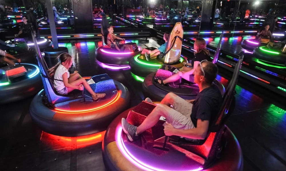 Modern electric bumper cars with colorful lighting inside an amusement arena.