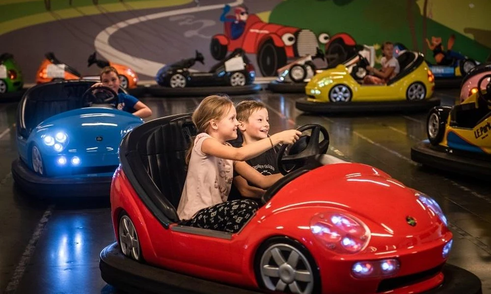 Children enjoying small colorful bumper cars at a family amusement attraction.