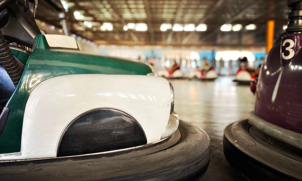 Close-up of bumper car rubber protection, steering wheel, and rider safety restraint.