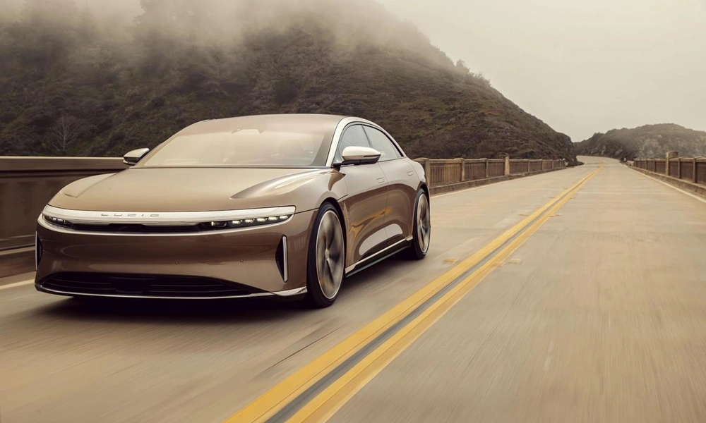Silver Lucid Air Grand Touring electric sedan driving along an open highway.