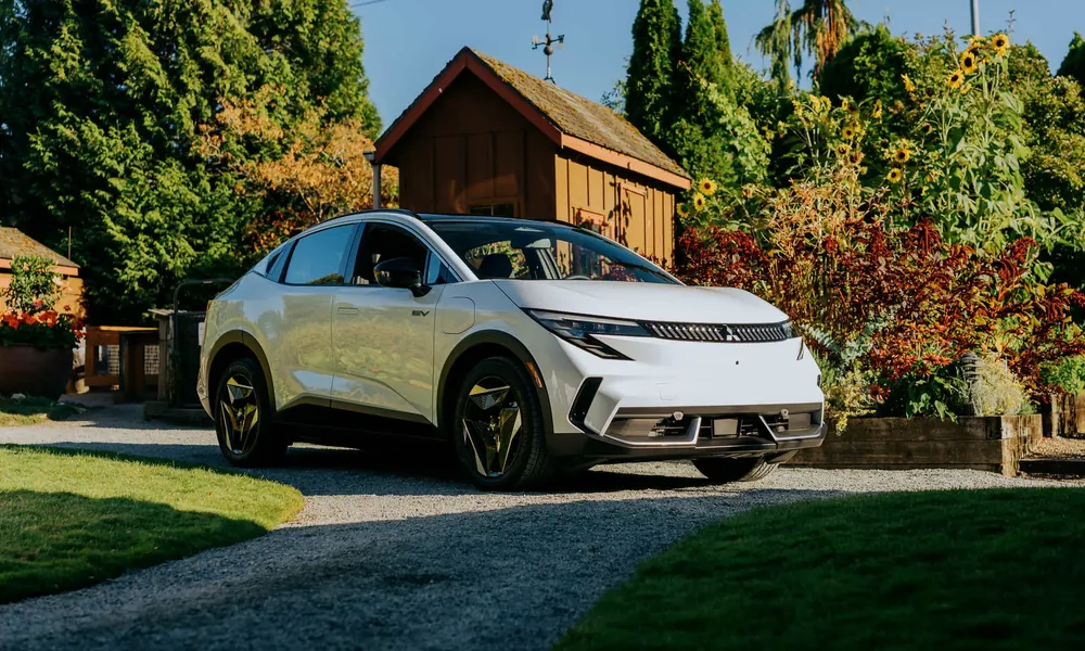 White Mitsubishi Eclipse Sportback electric crossover parked on a gravel driveway in a garden