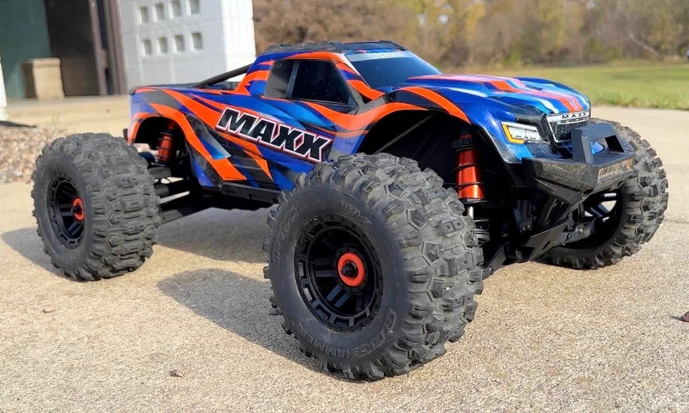 Traxxas Maxx RC monster truck landing a jump on dirt