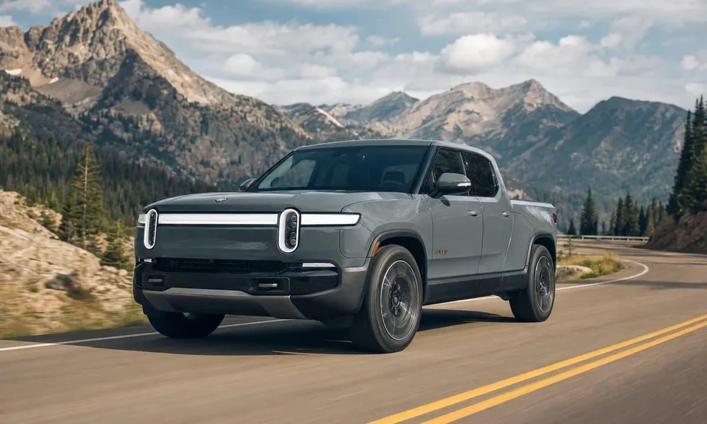 Rivian R1T electric pickup truck parked on a scenic mountain road.