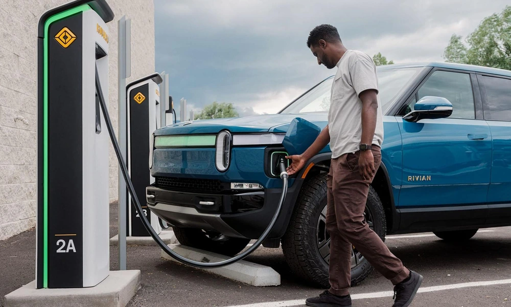 Rivian electric pickup truck connected to a public fast charging station.