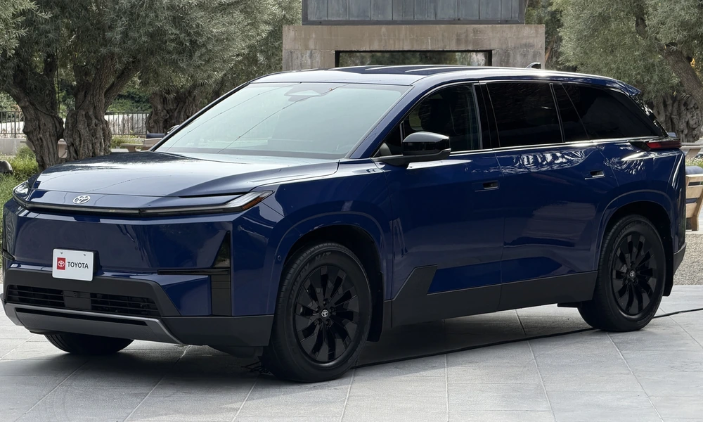 Dark blue Toyota Highlander EV parked on a paved area with olive trees behind it