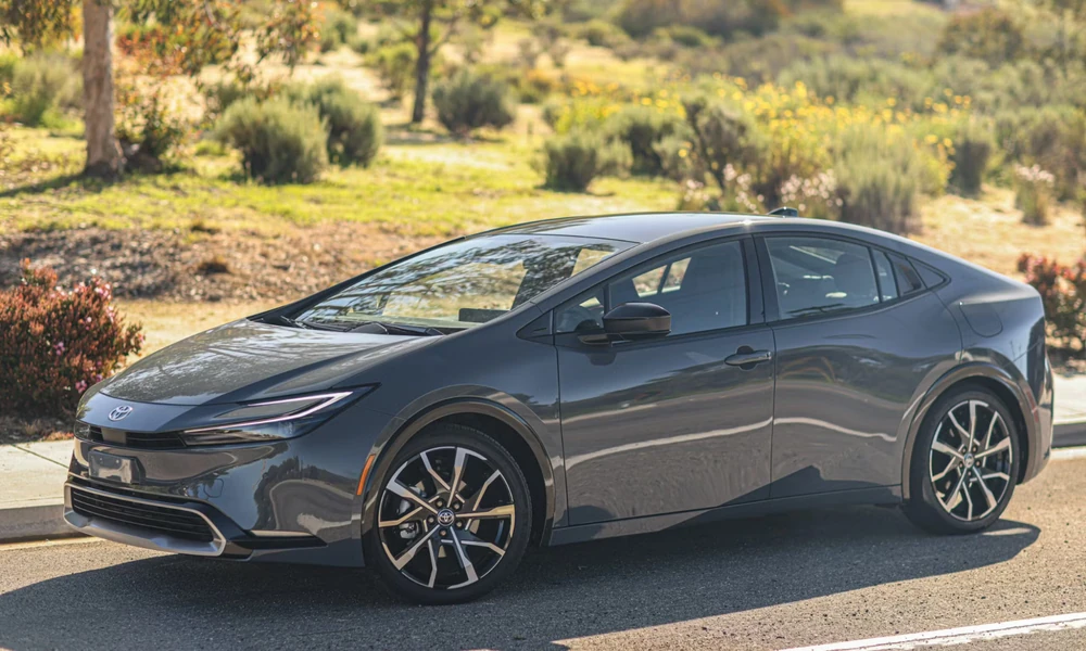 Dark gray Toyota Prius hatchback parked on a road with dry scrubland behind it