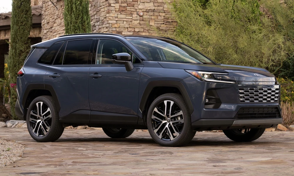 Dark gray Toyota RAV4 Hybrid SUV parked on a stone driveway near a stone building