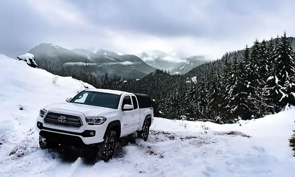 Pickup truck driving through snow on a winter road.