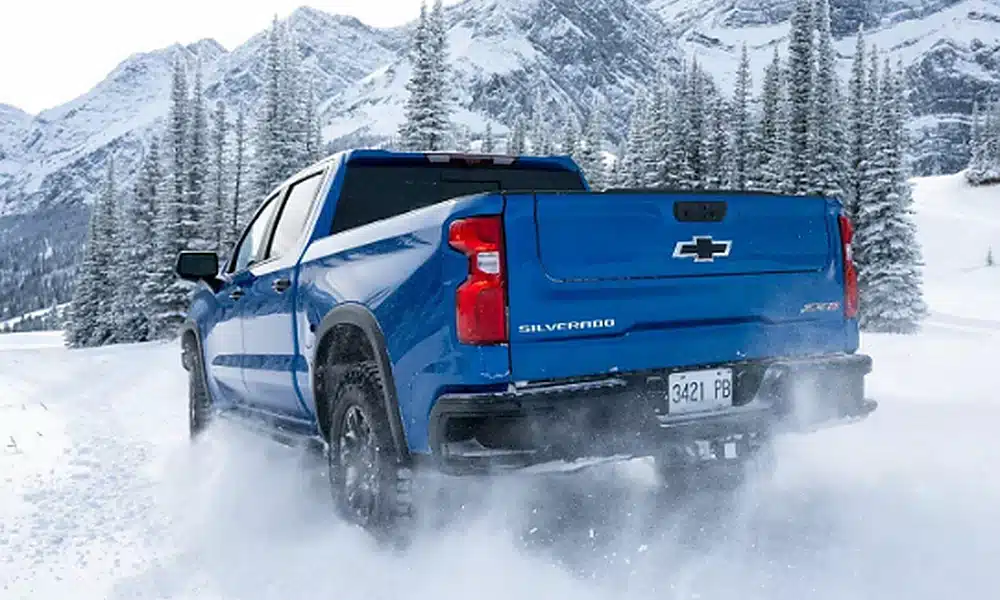 Blue Chevrolet Silverado 1500 pickup truck viewed from the rear in deep snow.
