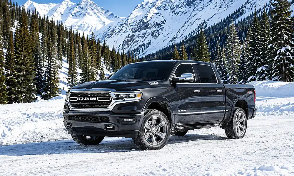 Grey Ram 1500 pickup truck parked on a snow-covered road surrounded by mountains.