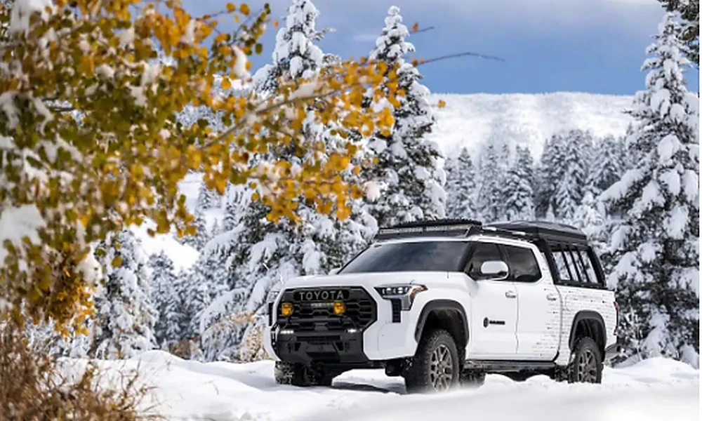 White Toyota off-road vehicle travelling through a snow-covered forest.